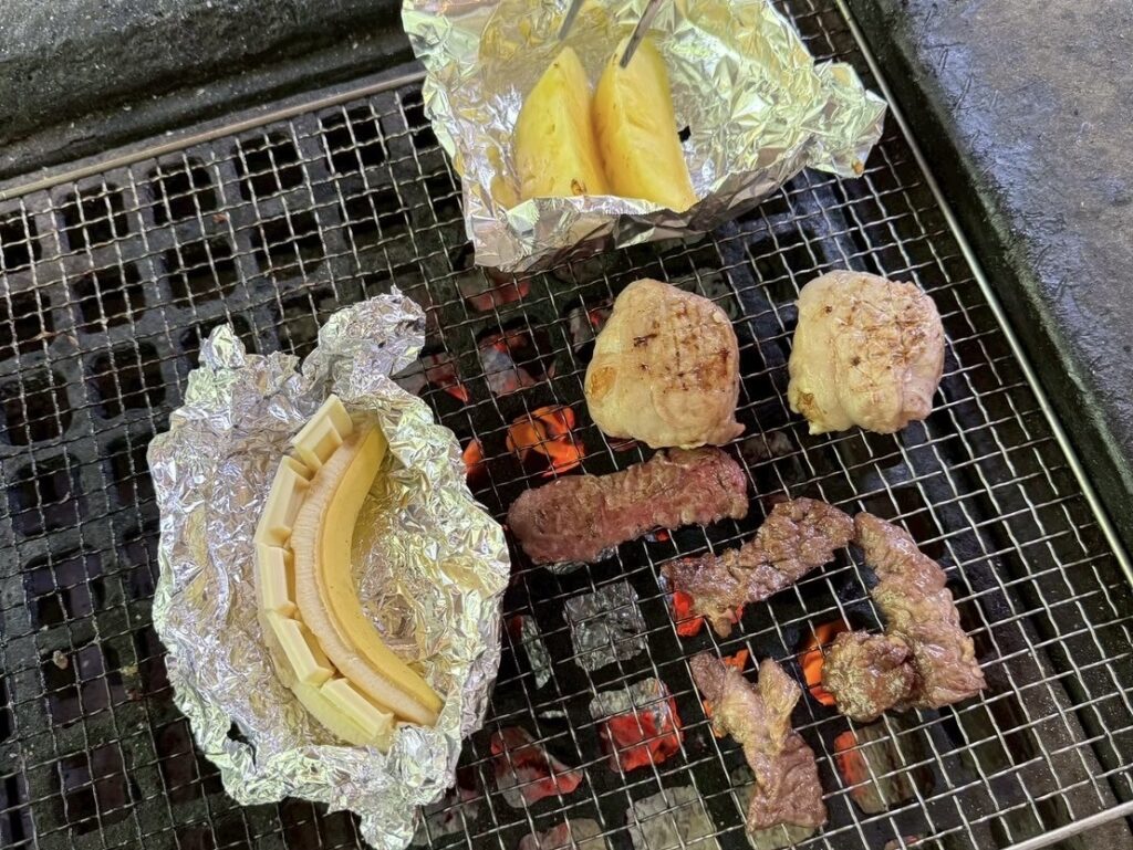 バーベキューで焼いている肉、肉巻きおにぎり、チョコバナナ、パイナップル